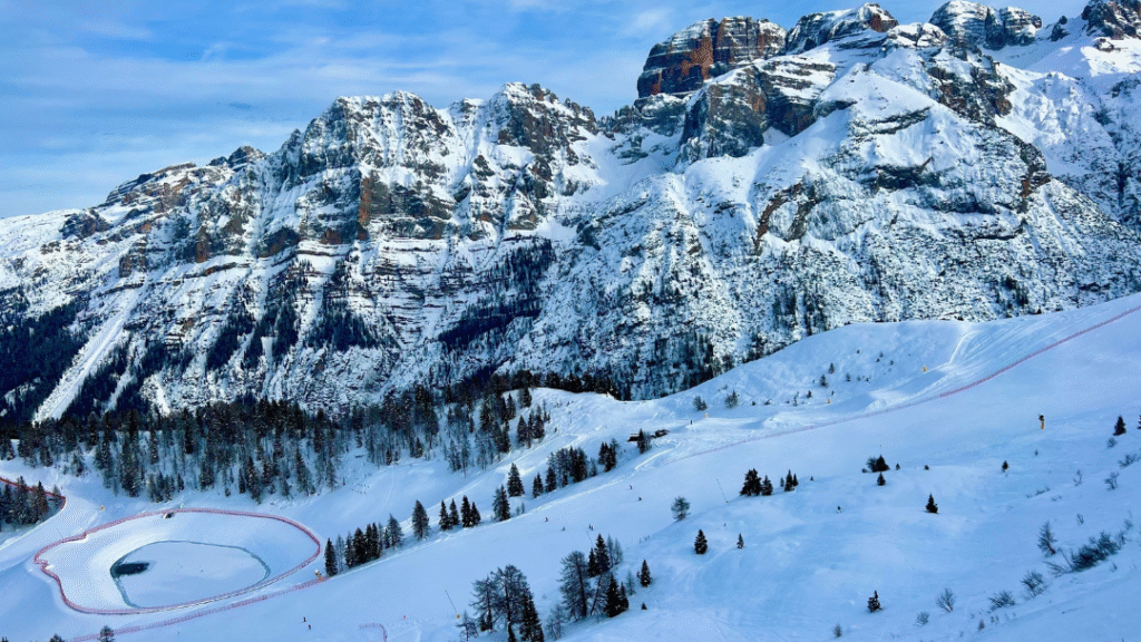 Panoramski pogled na zasnežene Dolomite v smučarskem središču Folgarida-Marilleva: široke urejene proge, modro nebo in veličastne gore. Popolna zimska idila!